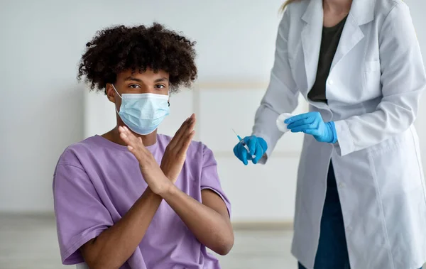 Adolescente afroamericano en mascarilla que impide al médico hacer la vacuna covid, estando en contra de la inmunización contra el coronavirus —  Fotos de Stock