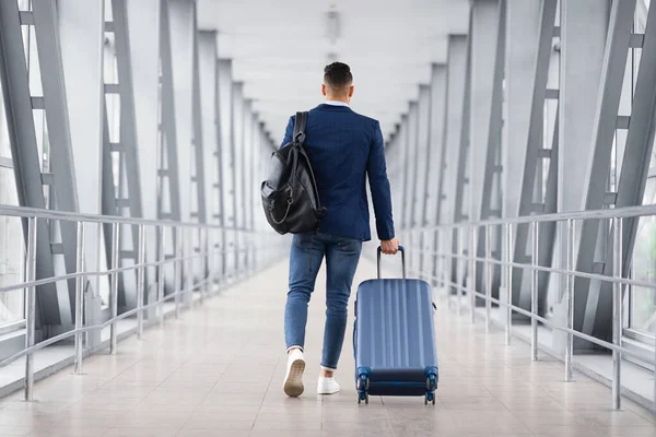 Hombre con ropa casual caminando con equipaje en la terminal del aeropuerto, vista trasera — Foto de Stock