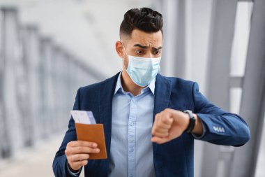 Kol saatine bakan maskeli endişeli bir Arap uçuşa geç kalıyor.