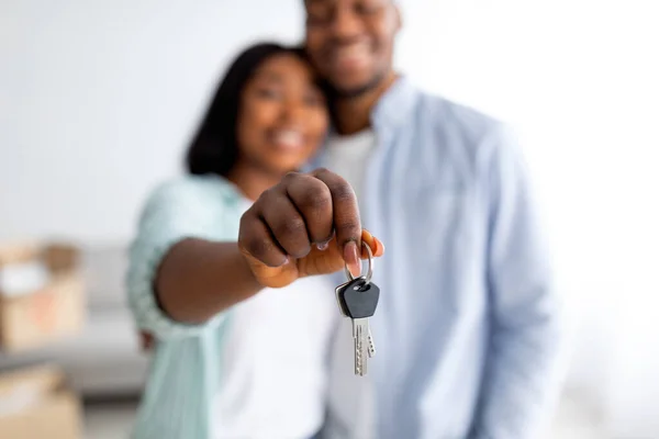 Concepto de vivienda familiar. Cónyuges afroamericanos felices sosteniendo nueva llave de la casa, foco selectivo, profundidad superficial —  Fotos de Stock