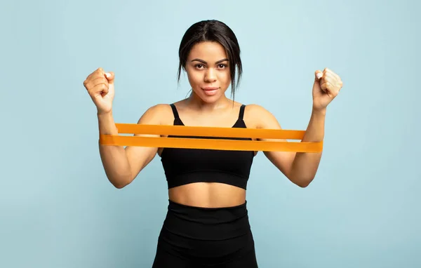 Strength and motivation. African american sportswoman doing exercises for hands, working out with resistance band — Stock Photo, Image