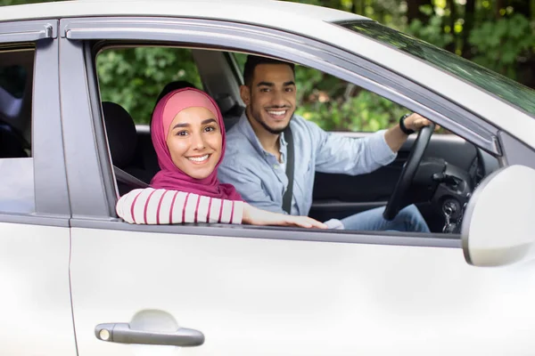 Portret van vrolijke moslimechtgenoten die in de auto zitten en glimlachen naar de camera — Stockfoto