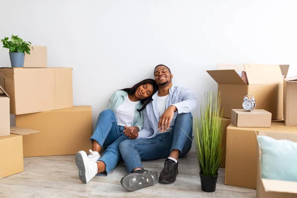 Conceito de renda, hipoteca e propriedade imobiliária. feliz casal preto sentado entre caixas de papelão, espaço livre — Fotografia de Stock