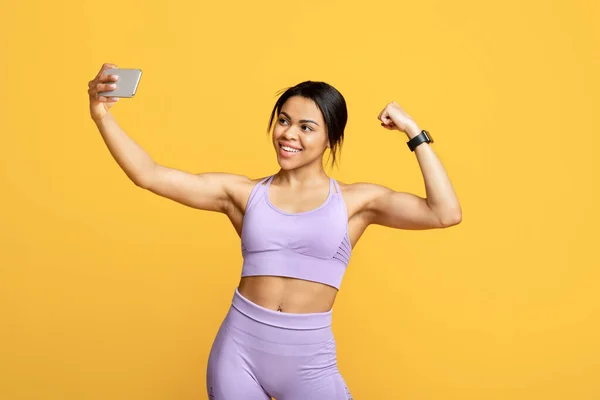 Antrenör blogcudan selfie. Spor giyim sektöründe mutlu formda bir zenci kadın blogu için akıllı telefondan fotoğraf çekiyor. — Stok fotoğraf