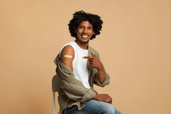 Coronavirus aşısı. Kolundaki yapıştırıcı bandajı gösteren genç siyah adam. — Stok fotoğraf