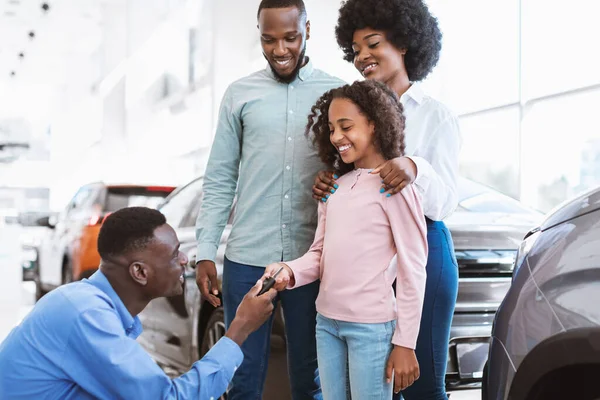 Família negra feliz comprar carro novo, vendedor dando-lhes a chave na concessionária de automóveis — Fotografia de Stock