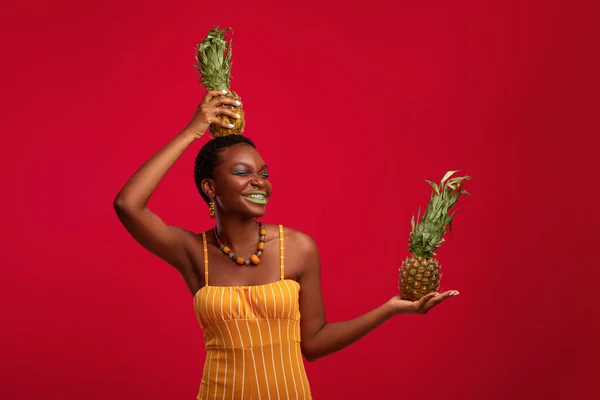 Ananaslarla poz veren komik Afrikalı Amerikalı genç kadın. — Stok fotoğraf