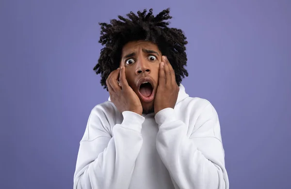 Czarny nastolatek facet uczucie przestraszony krzyki w panice na fioletowy studio tło — Zdjęcie stockowe