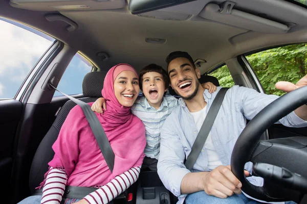 道路の楽しみ。車の中で一緒に歌う3人の楽しいイスラム教徒の家族 — ストック写真