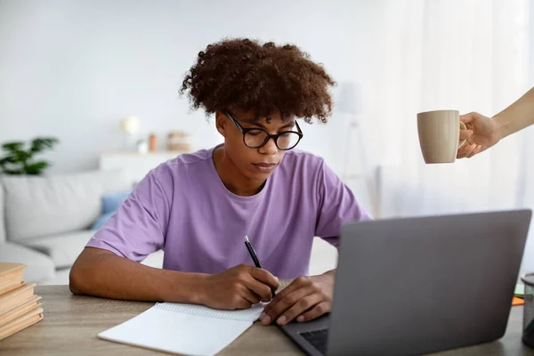 Grave preto teen cara escrevendo no notebook durante webinar ou lição no laptop em casa — Fotografia de Stock