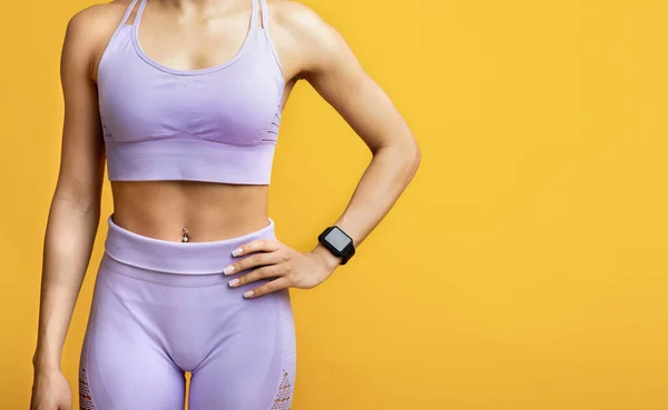 Sport livsstil koncept. ung passform kvinna i sportkläder med fitness tracker poserar över gul bakgrund, fritt utrymme — Stockfoto