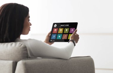 Elinde akıllı ev uygulaması olan Afrikalı Amerikalı bir kadın.