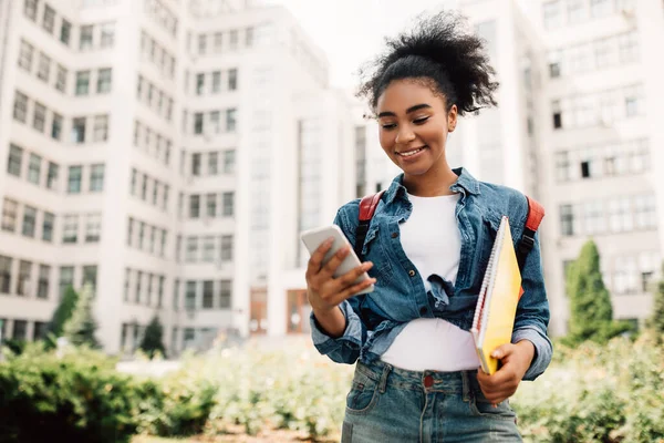 Gelukkig Afrikaans student meisje met behulp van telefoon met educatieve app buiten — Stockfoto