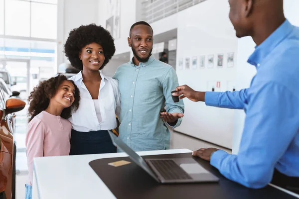 Salesman giving new car key to young Afro family at auto dealership. Vehicle local distribution concept — Stock Photo, Image