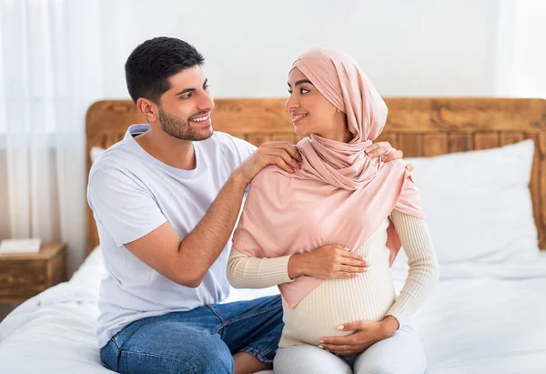 Těhotenská masáž. Pečující muslimský manžel masíruje ramena své mladé šťastné těhotné manželky — Stock fotografie