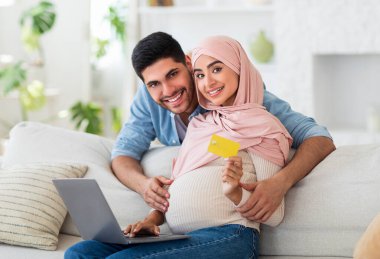 Doğuma hazırlanıyorum. Mutlu Müslümanlar ailelerini dizüstü bilgisayar ve kredi kartı kullanarak evde alışveriş yaparak bekliyor.