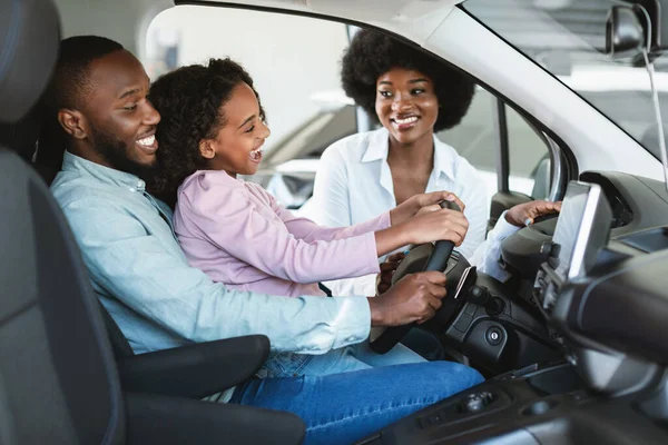 Alegre família negra sentada em carro novo, indo em test drive, comprando automóvel na concessionária — Fotografia de Stock