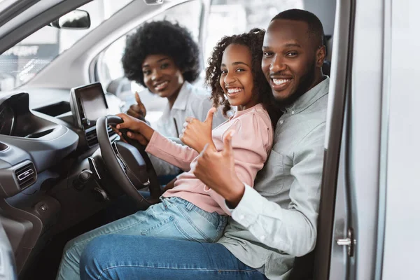 Família feliz mostrando polegares para cima no assento do motorista do carro, verificando auto salão antes de comprar o veículo, recomendando concessionária — Fotografia de Stock