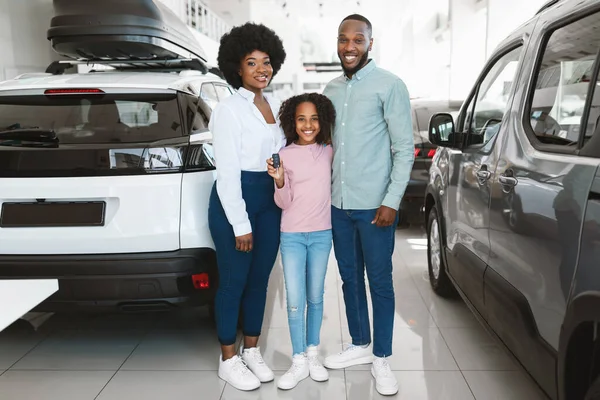 Comprimento total da chave segurando da família preta feliz, comprando o carro novo na concessionária do automóvel — Fotografia de Stock