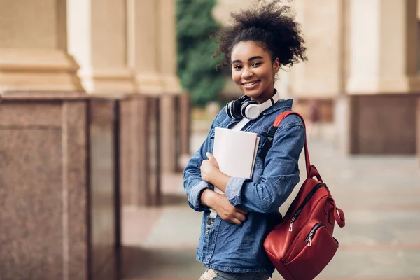 Glada svarta student flicka kramar böcker Posing nära College Building — Stockfoto