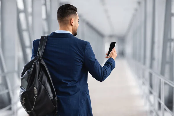 Reserva Hotel Online. Hombre árabe con mochila usando un teléfono inteligente en blanco en el aeropuerto — Foto de Stock