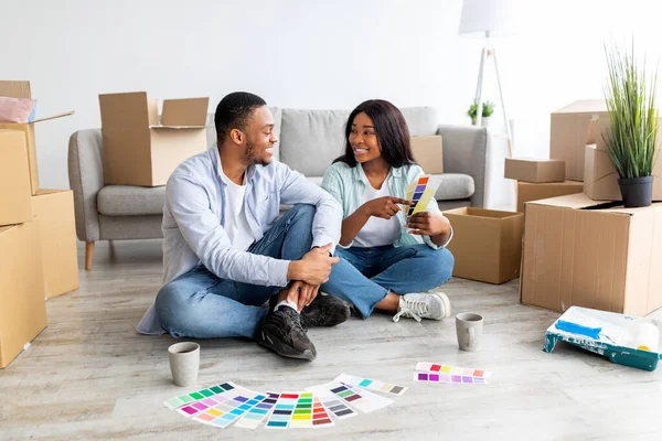 Creative african american spouses working on design for their house, discussing color palette while sitting among boxes — Stock Photo, Image