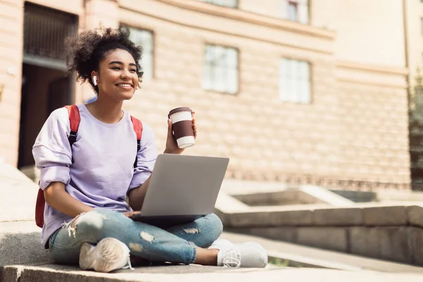 Africana estudiante chica usando portátil celebración café aprendizaje en línea al aire libre — Foto de Stock