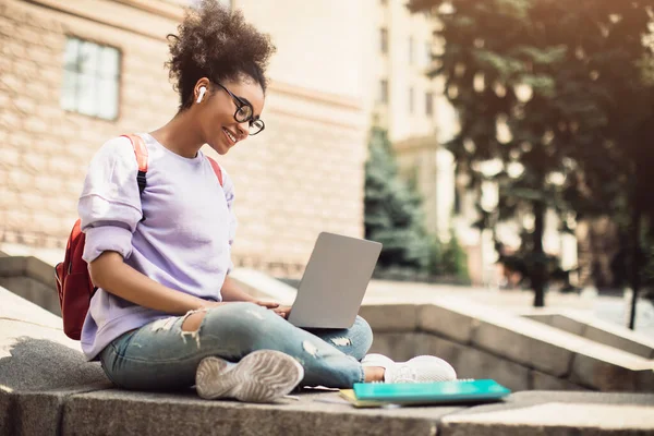 Vista lateral de estudiante negro con portátil que mira Webinar educativo al aire libre — Foto de Stock