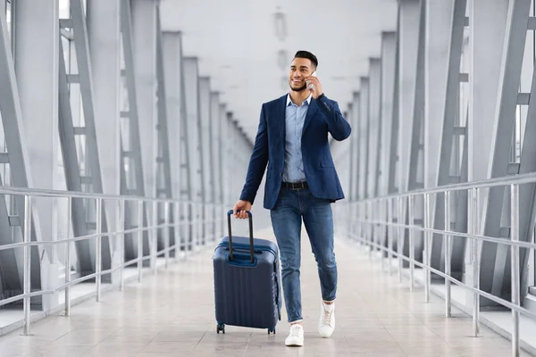 Bonito homem árabe andando com mala no aeroporto e falando no celular — Fotografia de Stock