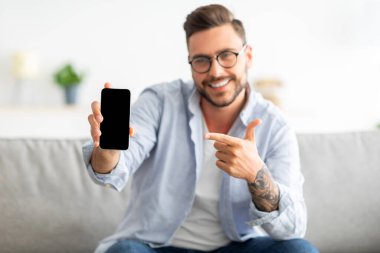 Akıllı telefon maketi. Milenyum adamı cep telefonunu boş ekranla gösteriyor ve parmağıyla işaret ediyor.