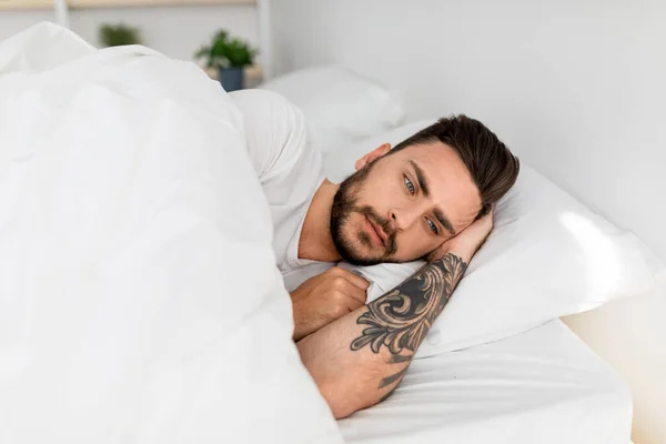 Trieste duizendjarige man alleen in bed, lijden aan eenzaamheid en denken aan problemen, kopieer ruimte — Stockfoto