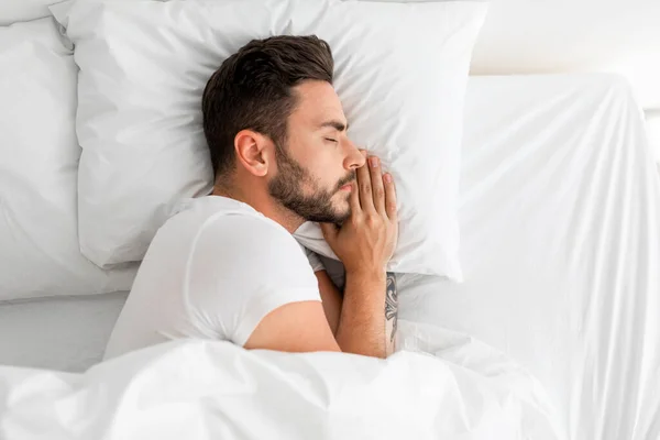 Schlafender Millennial-Mann schlafend, friedlich in bequemem Bett liegend, mit geschlossenen Augen, von oben gesehen, freier Raum — Stockfoto