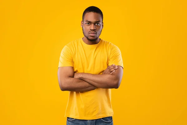 Hombre afroamericano serio posando cruzando las manos sobre fondo amarillo — Foto de Stock