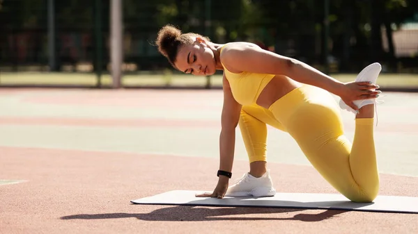 Deportiva mujer negra en amarillo ropa deportiva estiramiento pierna — Foto de Stock