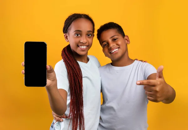 Очаровательные черные подростки брат и сестра показывают смартфон, макет — стоковое фото