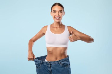 Yaşlı, geniş pantolonunu çekip Başparmaklarını Gösteren Kadın