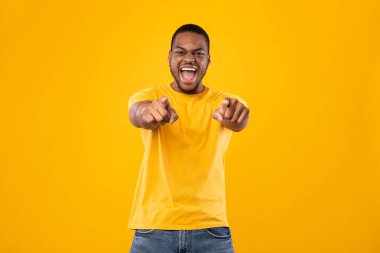 Afrikalı adam iki eliyle kamerayı, stüdyoyu işaret ediyor.