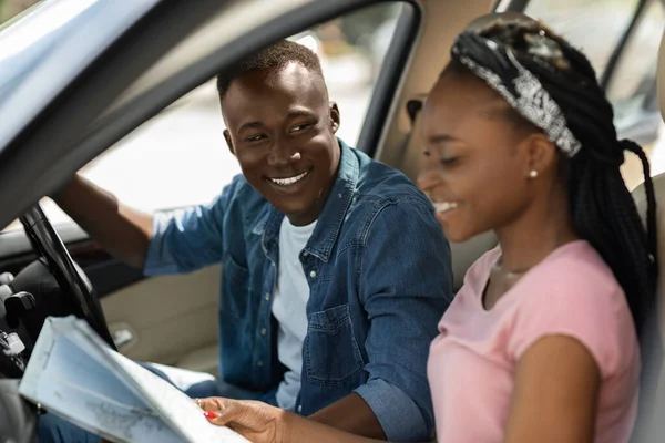 Emocionados viajeros afro-americanos en pareja mirando el mapa mientras conducen — Foto de Stock