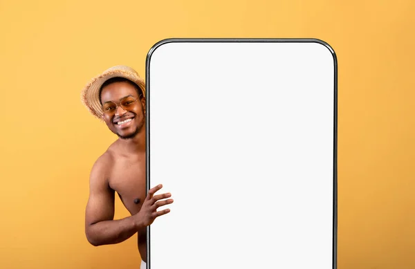 Hombre negro mostrando la pantalla del teléfono inteligente blanco vacío y espiando —  Fotos de Stock