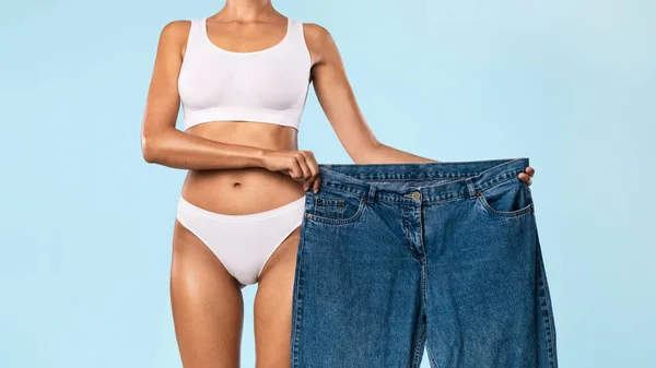 Fit Woman trzyma swoje stare duże luźne dżinsy — Zdjęcie stockowe