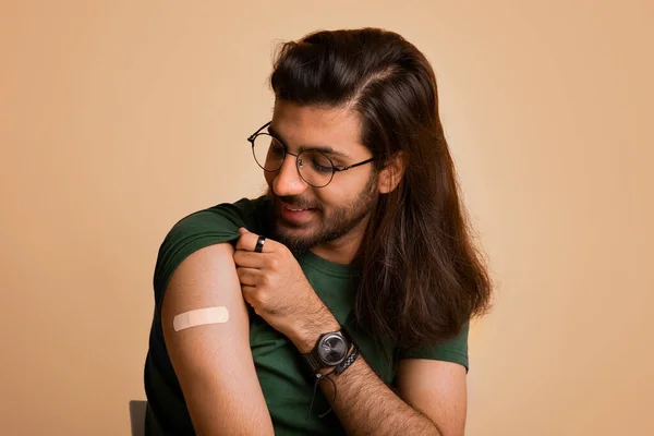 Gezonde man uit het Midden-Oosten kijkt naar een medische band op zijn schouder — Stockfoto