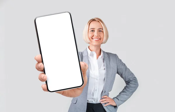 Mulher de negócios mostrando fechamento de tela de smartphone vazio para câmera — Fotografia de Stock