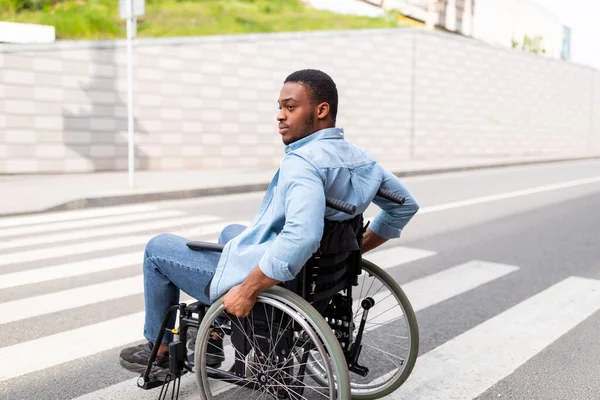 Életminőség és romlás. Millenniumi mozgássérült fekete férfi tolószékben a zebrán ősszel — Stock Fotó