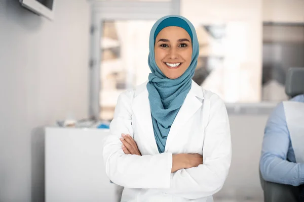 Стоматологічна служба. Портрет усміхненої ісламської жінки - стоматолога, що стоїть зі слідом за зброєю — стокове фото