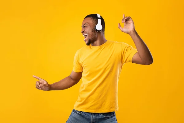 Africano macho tener divertido bailando disfrutando música sobre amarillo fondo — Foto de Stock