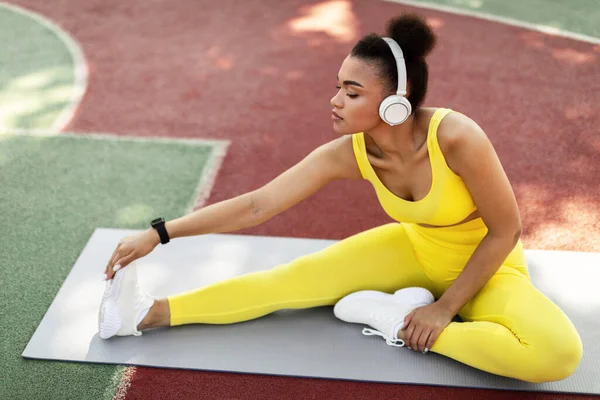 Μαύρη γυναίκα σε κίτρινο αθλητικό ένδυμα τεντωμένο πόδι έξω — Φωτογραφία Αρχείου