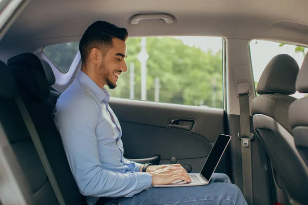Young Arab man VD arbetar på bil baksäte, med hjälp av bärbar dator — Stockfoto
