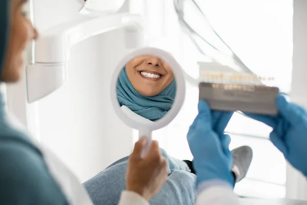 Mulher Muçulmana bonita no Hijab olhando para o espelho no escritório de dentistas — Fotografia de Stock