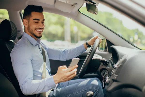 Allegro arabo uomo utilizzando il cellulare durante la guida di auto — Foto Stock