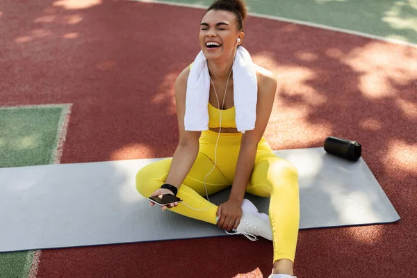 Deportiva mujer negra en ropa deportiva amarilla escuchando música — Foto de Stock